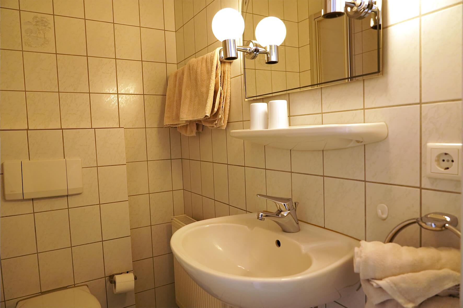 Aufnahme eines gefliesten Badezimmers in weiß mit Waschbecken und Spiegel