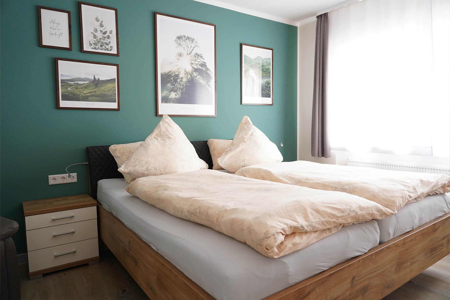 modernes Zimmer mit waldgrüner Wand mit Naturbilder und einem Holzbett davor