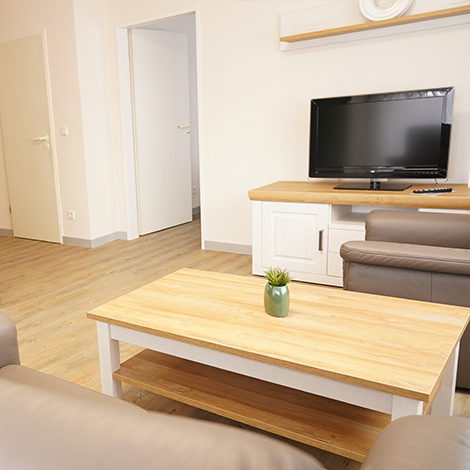 Wohnzimmerbereich mit grau/braunen Ledersofa, Couchtisch in Holz mit weiß und einem Flachbildschirmfernseher