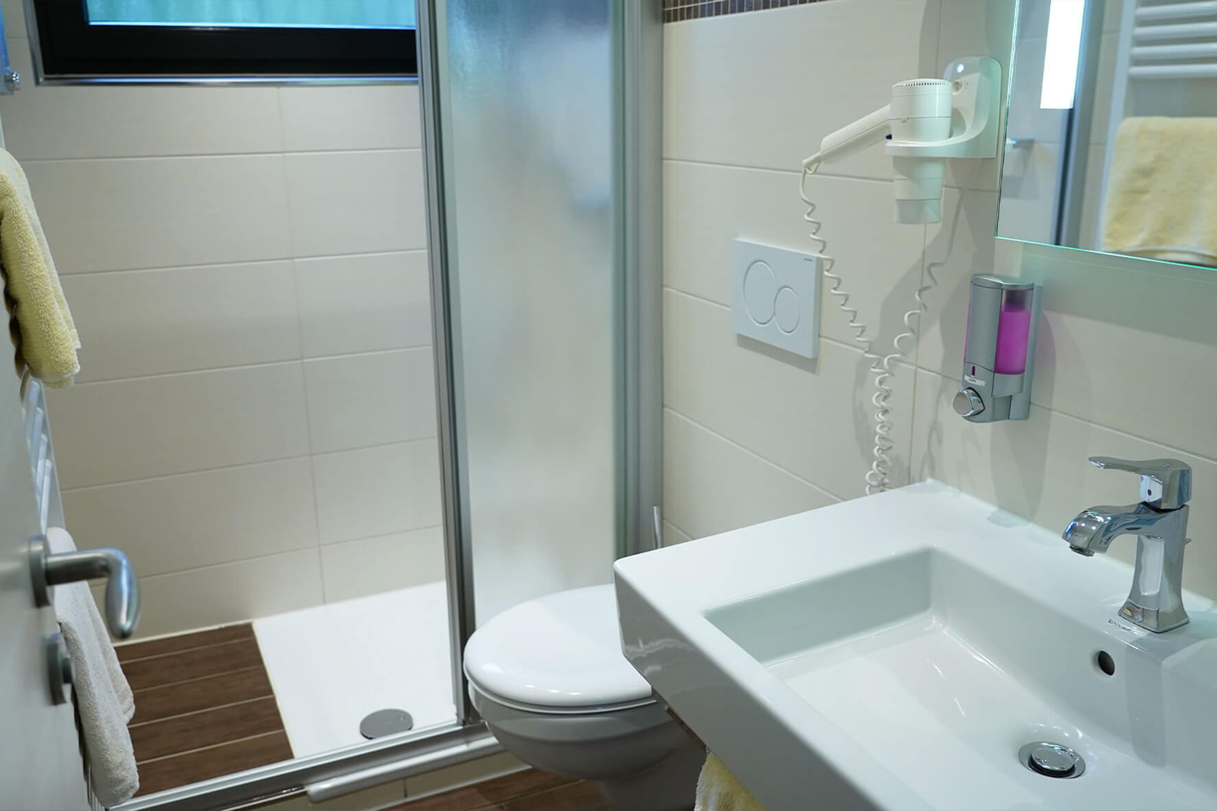 Weiß gefliestes Bad mit Waschbecken, Dusche und Toilette